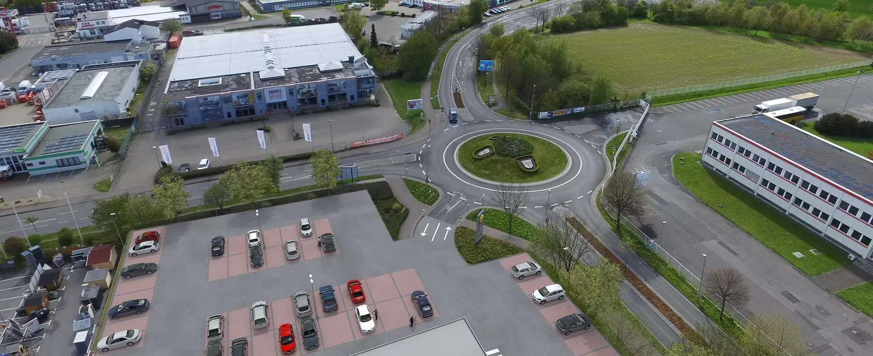 Luftaufnahme eines Fachmarktzentrums mit Kreisverkehr und Parkflächen