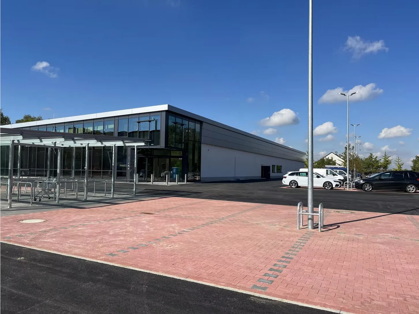 Fertiggestellter Einzelhandelsmarkt mit Glasfassade, Parkplatz und Einkaufswagen-Unterstand